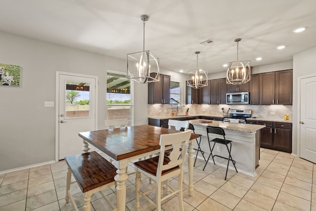 dining space with a chandelier, recessed lighting, light tile patterned flooring, and baseboards