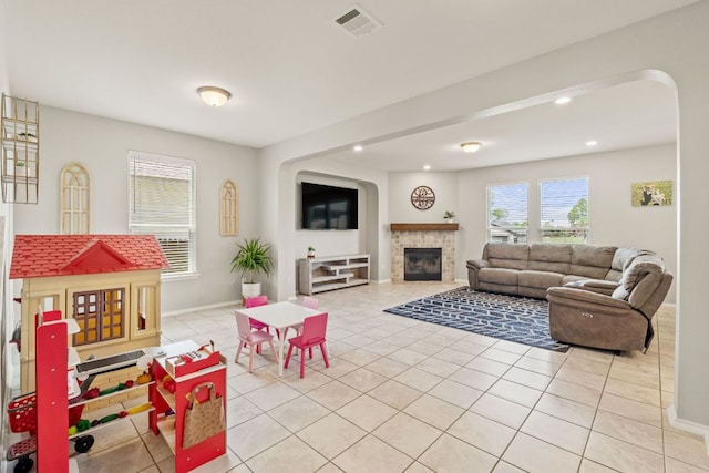 living area featuring light tile patterned floors, baseboards, recessed lighting, and a glass covered fireplace
