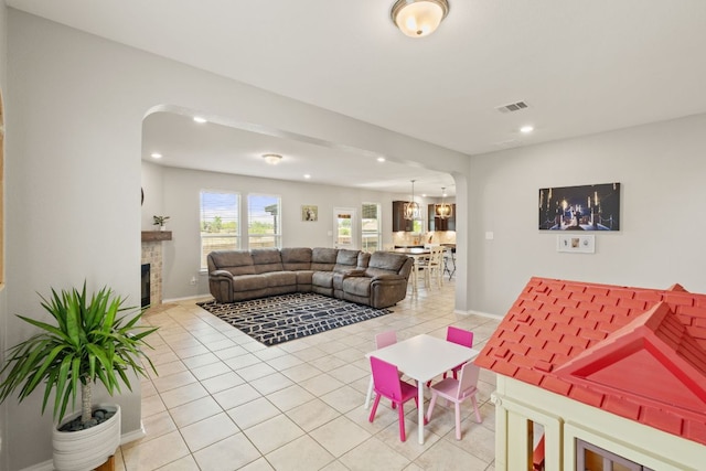 living room featuring arched walkways, light tile patterned flooring, recessed lighting, a fireplace, and baseboards