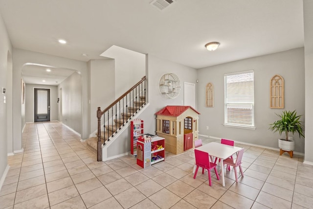 game room featuring light tile patterned flooring, arched walkways, recessed lighting, and baseboards