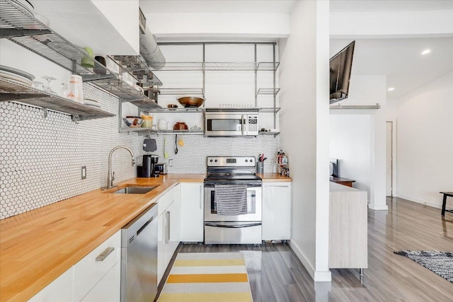 1304 Mariposa Dr Unit 214, Austin, TX 78704 - kitchen featuring appliances with stainless steel finishes, light wood-style flooring, backsplash, white cabinets, and recessed lighting