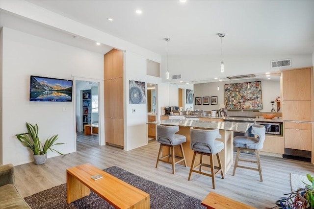1304 Mariposa Dr Unit 215, Austin, TX 78704 - kitchen featuring stainless steel microwave, modern cabinets, light countertops, light wood-style flooring, and a kitchen bar