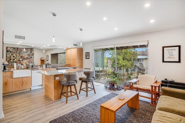 1304 Mariposa Dr Unit 215, Austin, TX 78704 - kitchen with white dishwasher, recessed lighting, light wood-style floors, a center island, and a breakfast bar