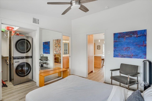 1304 Mariposa Dr Unit 215, Austin, TX 78704 - bedroom featuring stacked washing machine and dryer, light wood finished floors, a ceiling fan, and ensuite bathroom