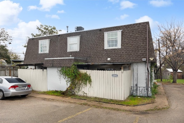 2201 Mission Hill Cir, Austin, TX 78741 - view of front of property with a shingled roof, mansard roof, fence, and brick siding