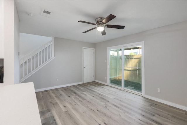 2201 Mission Hill Cir, Austin, TX 78741 - unfurnished living room featuring wood finished floors, baseboards, stairway, and ceiling fan