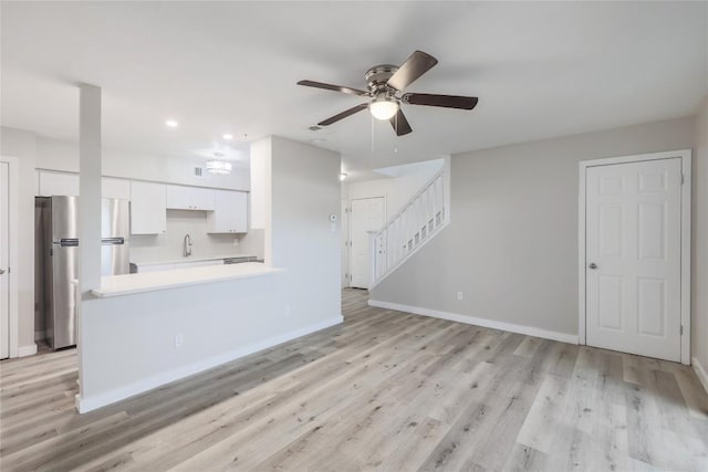 2201 Mission Hill Cir, Austin, TX 78741 - unfurnished living room with a ceiling fan, light wood-style flooring, baseboards, recessed lighting, and stairway