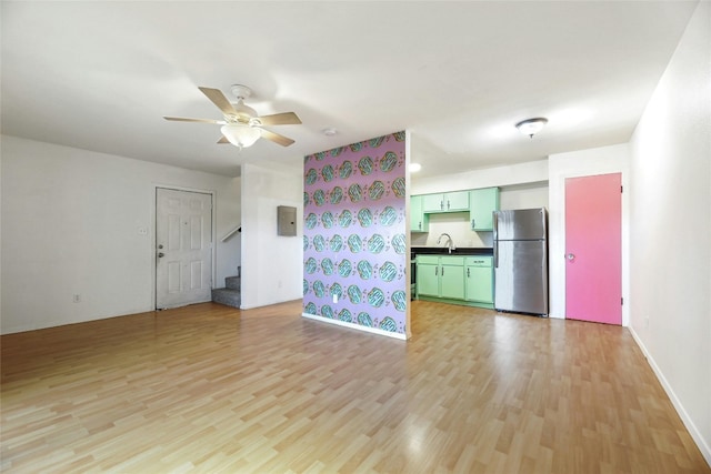 2201 Mission Hill Cir, Austin, TX 78741 - unfurnished living room with light wood-style flooring, a sink, stairs, a ceiling fan, and baseboards