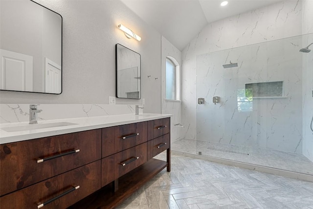 bathroom with vaulted ceiling, a marble finish shower, and double vanity