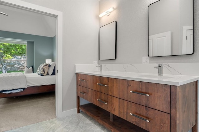 full bath with connected bathroom, double vanity, and baseboards