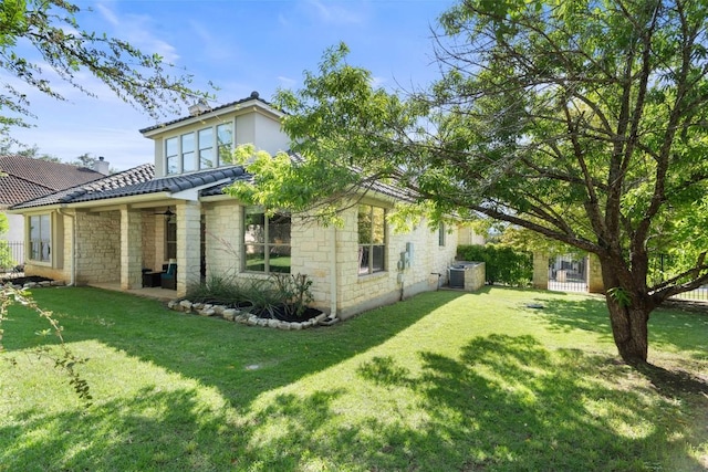 back of property with stone siding, a tile roof, and a yard