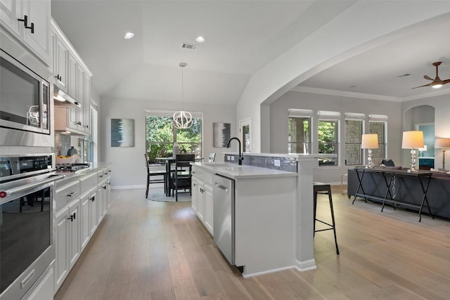 kitchen with stainless steel appliances, a sink, a kitchen breakfast bar, light countertops, and light wood-style flooring