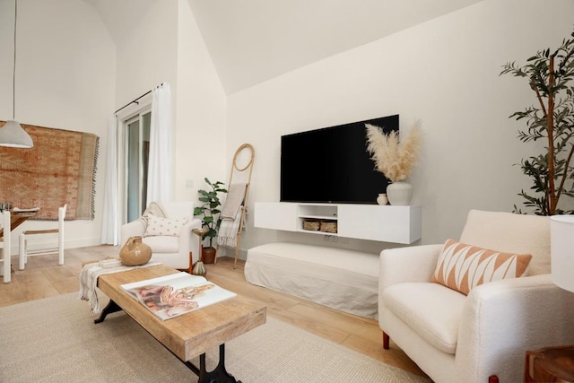 living area with wood finished floors, high vaulted ceiling, and baseboards