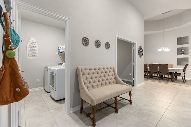 washroom featuring washing machine and dryer, light tile patterned flooring, a chandelier, a towering ceiling, and baseboards