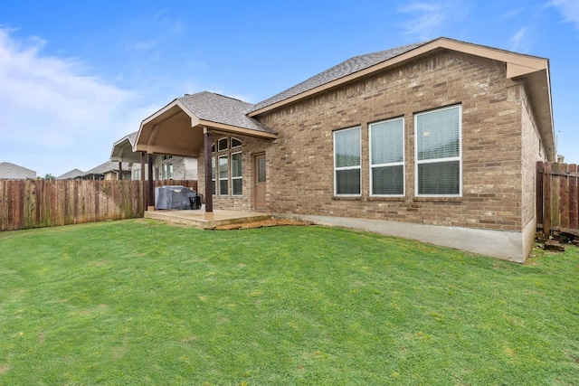 back of property with brick siding, a patio area, and a shingled roof