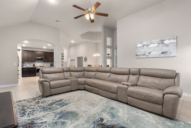 living area with light tile patterned flooring, ceiling fan, arched walkways, baseboards, and high vaulted ceiling