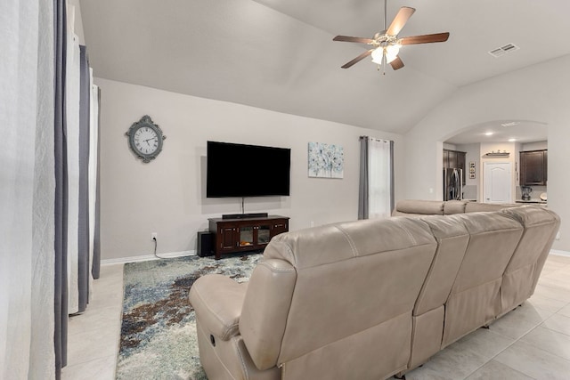 living room with light tile patterned floors, arched walkways, a ceiling fan, lofted ceiling, and baseboards