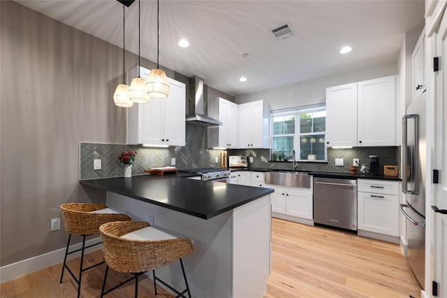 7812 Mullen Dr Unit 2, Austin, TX 78757 - kitchen with wall chimney exhaust hood, stainless steel appliances, a sink, a peninsula, and dark countertops