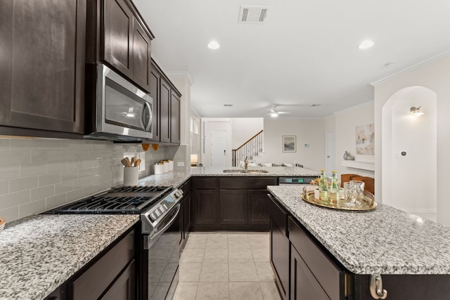 9528 Hunter Ln, Austin, TX 78748 - kitchen featuring stainless steel appliances, ornamental molding, tasteful backsplash, dark brown cabinets, and a peninsula