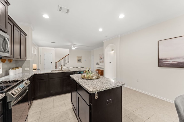 9528 Hunter Ln, Austin, TX 78748 - kitchen with stainless steel appliances, a sink, a peninsula, ornamental molding, and light stone counters