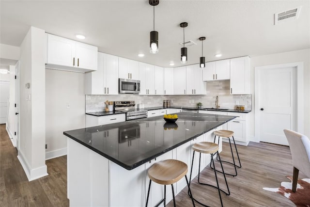 2003 Carriage Club Dr, Cedar Park, TX 78613 - kitchen featuring stainless steel appliances, wood finished floors, a center island, tasteful backsplash, and recessed lighting