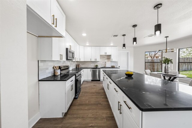 2003 Carriage Club Dr, Cedar Park, TX 78613 - kitchen with appliances with stainless steel finishes, a large island, backsplash, recessed lighting, and dark wood-type flooring