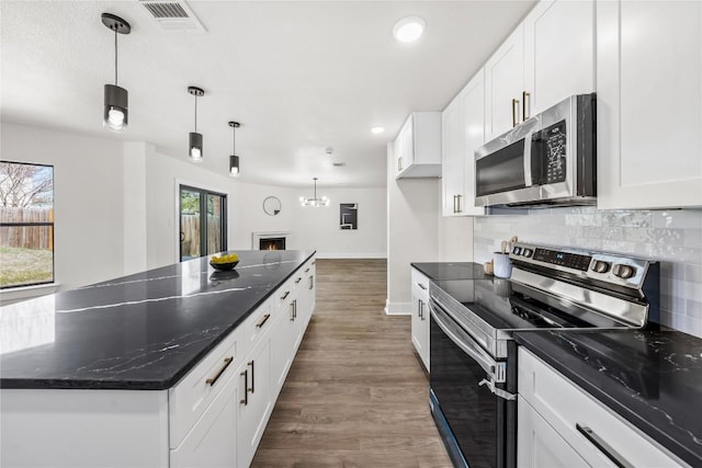 2003 Carriage Club Dr, Cedar Park, TX 78613 - kitchen with appliances with stainless steel finishes, a kitchen island, recessed lighting, white cabinetry, and dark wood finished floors