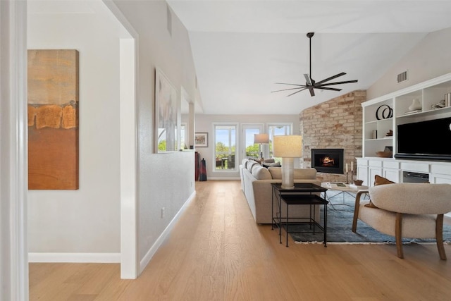 8900 Rockcrest Dr, Austin, TX 78759 - living area featuring a ceiling fan, light wood-type flooring, a stone fireplace, lofted ceiling, and baseboards