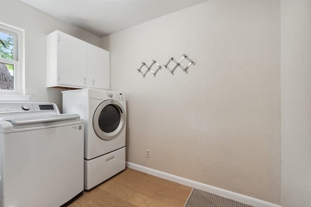 8900 Rockcrest Dr, Austin, TX 78759 - washroom with washer and clothes dryer, cabinet space, light wood-style floors, and baseboards