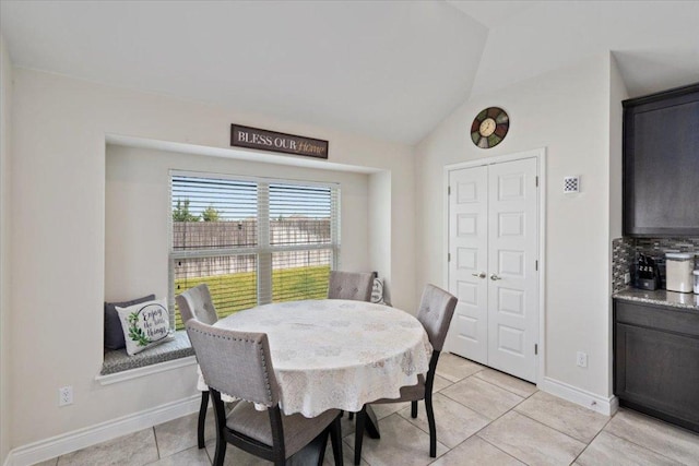 dining room with light tile patterned flooring, lofted ceiling, and baseboards