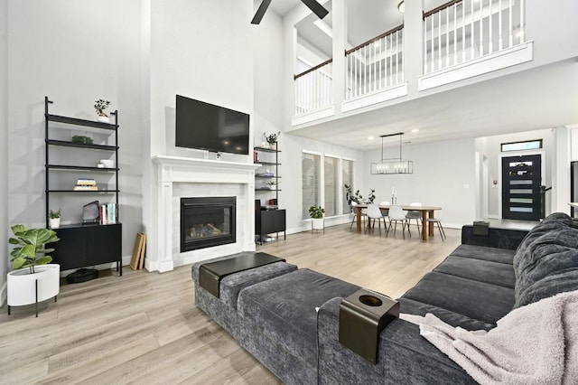 16708 Rakesh Way, Manor, TX 78653 - living room with wood finished floors, a towering ceiling, a glass covered fireplace, baseboards, and a chandelier