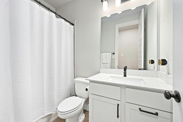 full bath with toilet, vanity, a textured wall, and a shower with curtain
