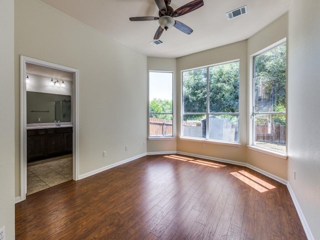 spare room featuring dark wood-type flooring, ceiling fan, baseboards, and a sink