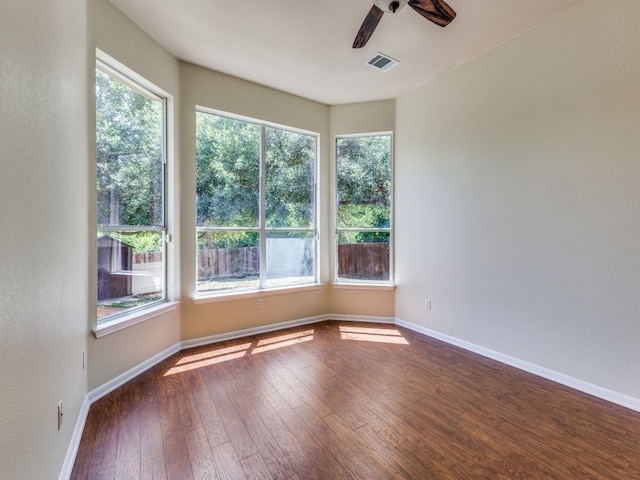 empty room with ceiling fan, dark wood-type flooring, healthy amount of natural light, and baseboards