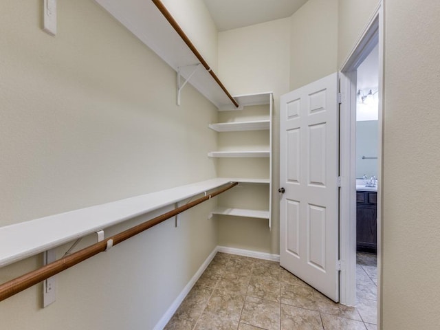 spacious closet with light tile patterned floors and a sink