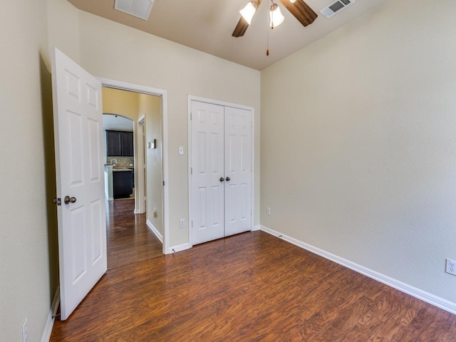 unfurnished bedroom featuring wood finished floors, baseboards, a closet, and ceiling fan