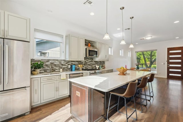 906 Linden St Unit A, Austin, TX 78702 - kitchen with stainless steel appliances, a sink, a center island, backsplash, and wood finished floors