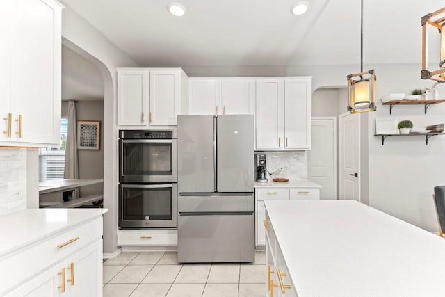 1116 Brenham Ln, Leander, TX 78641 - kitchen featuring freestanding refrigerator, stainless steel double oven, arched walkways, light countertops, and recessed lighting