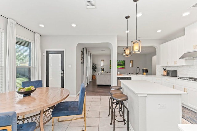 1116 Brenham Ln, Leander, TX 78641 - kitchen featuring arched walkways, a sink, light tile patterned floors, light countertops, and a center island