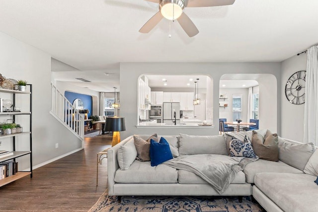 1116 Brenham Ln, Leander, TX 78641 - living area with arched walkways, dark wood-style floors, stairway, ceiling fan, and baseboards