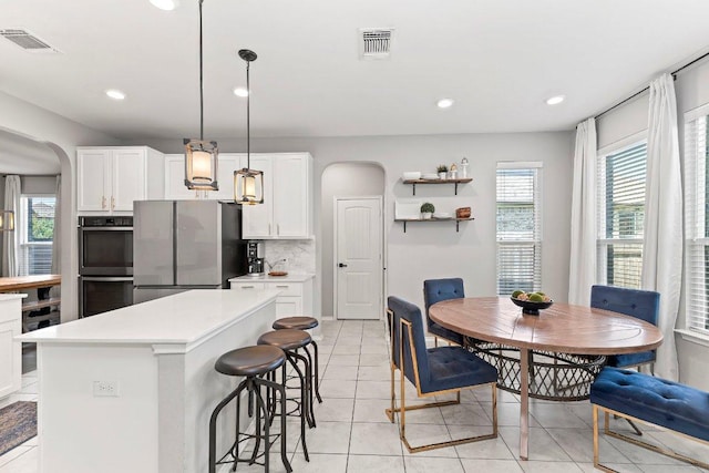 1116 Brenham Ln, Leander, TX 78641 - kitchen featuring arched walkways, freestanding refrigerator, white cabinets, light countertops, and a kitchen breakfast bar
