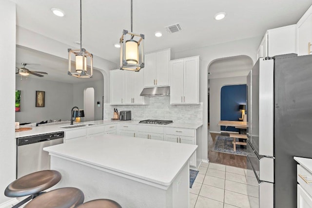 1116 Brenham Ln, Leander, TX 78641 - kitchen featuring stainless steel appliances, a sink, arched walkways, under cabinet range hood, and a ceiling fan