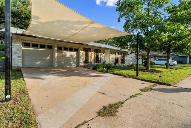 6905 Whispering Oaks Dr, Austin, TX 78745 - view of front of house featuring stone siding, driveway, a garage, and a front lawn