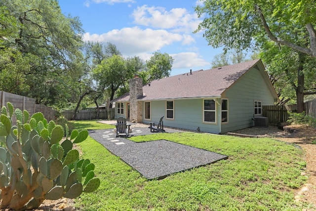 rear view of house with a patio, a chimney, central AC unit, and a shingled roof