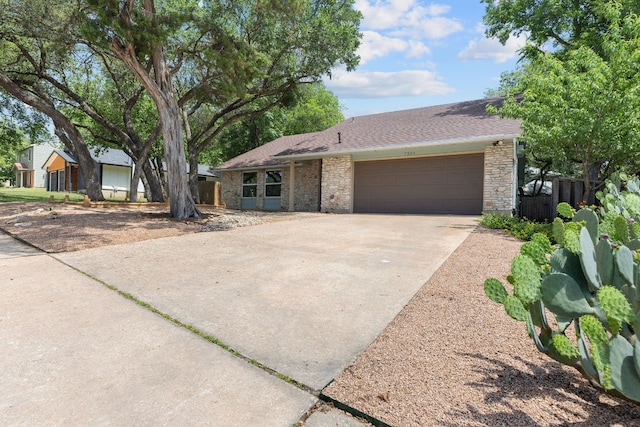 7805 Manassas Dr, Austin, TX 78745 - view of front of home with an attached garage, concrete driveway, stone siding, and a shingled roof