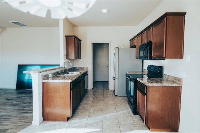 kitchen featuring black appliances, a sink, ceiling fan, light stone countertops, and a peninsula