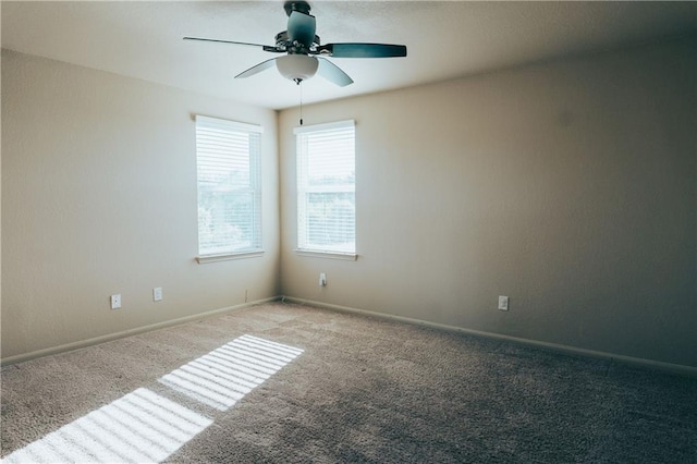 carpeted empty room featuring a ceiling fan and baseboards