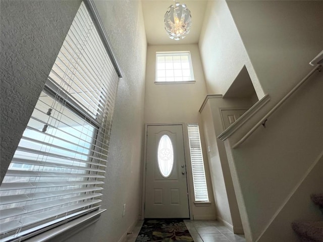 192 Falcon Dr, Luling, TX 78648 - entrance foyer with a chandelier, a textured wall, tile patterned floors, baseboards, and a high ceiling
