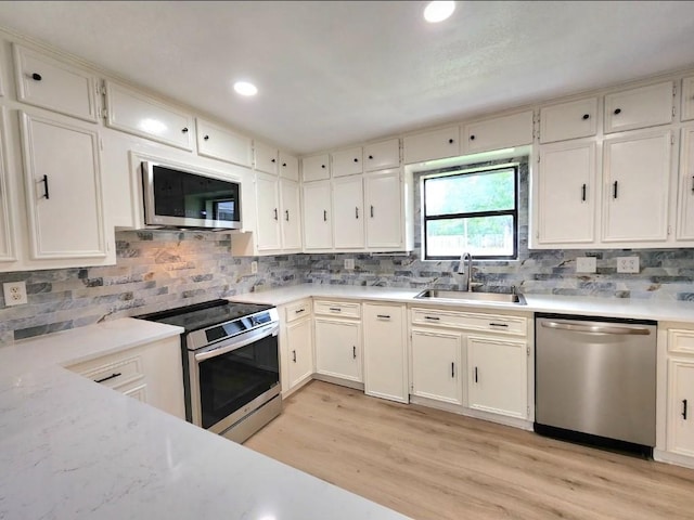 1011 N State Highway 95 N, Bastrop, TX 78602 - kitchen with appliances with stainless steel finishes, a sink, backsplash, light wood finished floors, and white cabinetry