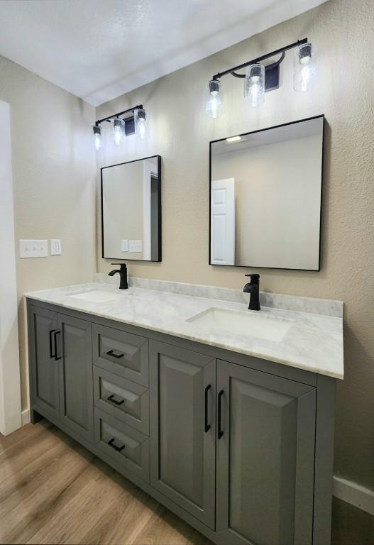 bathroom with wood finished floors, double vanity, and baseboards